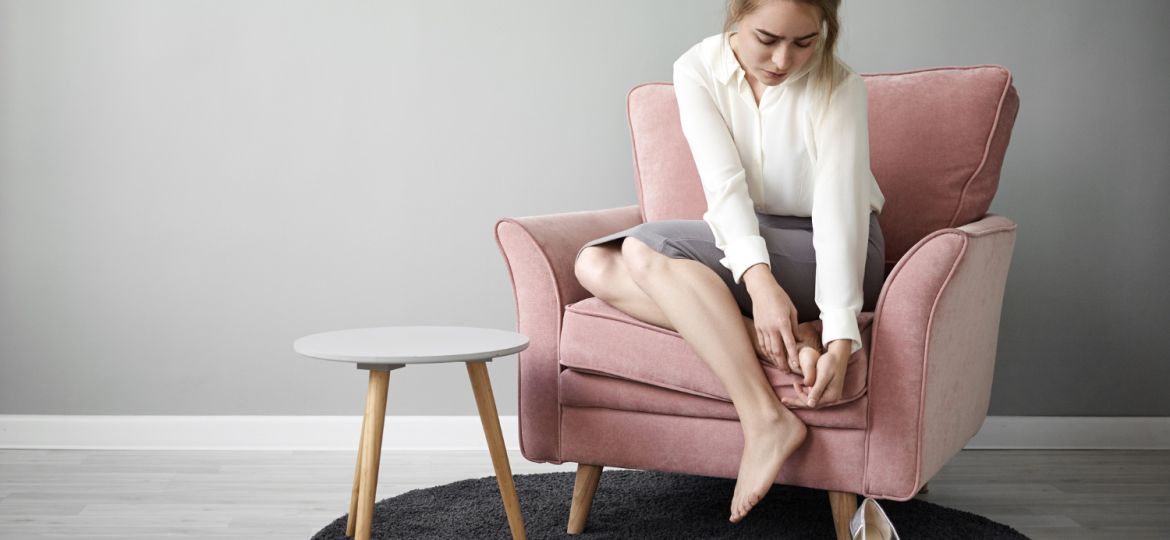 portrait-tired-exhausted-young-female-office-worker-formal-wear-sitting-armchair-massaging-her-foot-relieve-pain-because-wearing-high-heeled-shoes-all-day-health-wellness